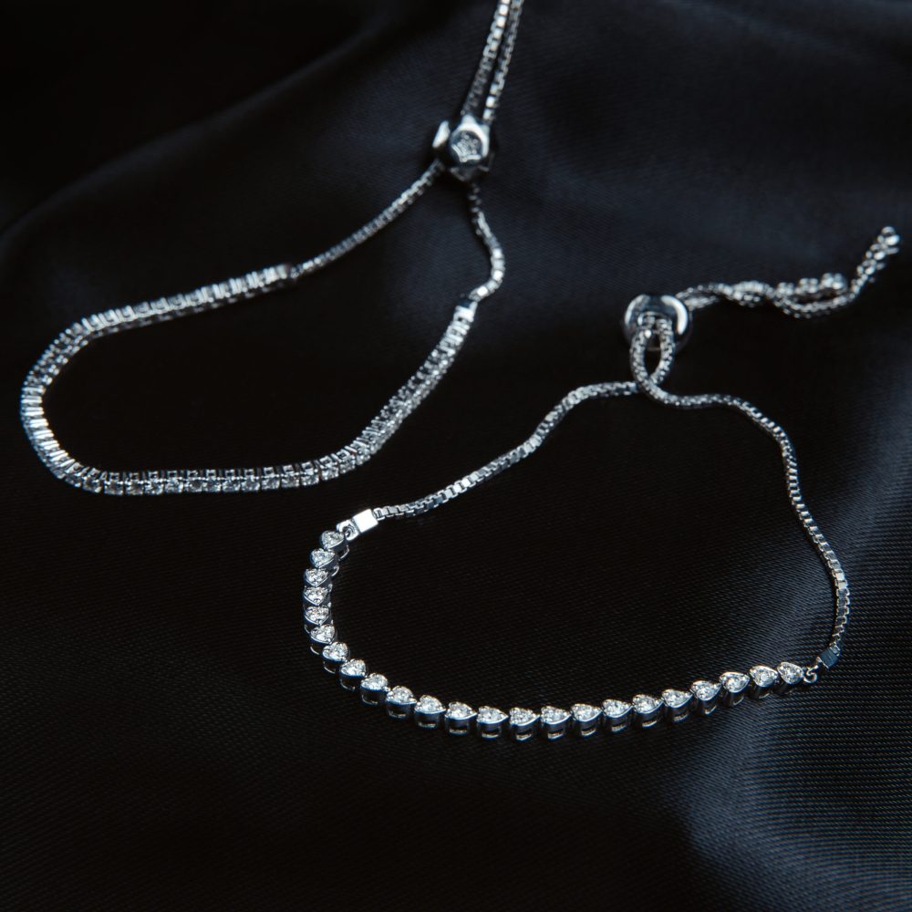 side view of silver bracelets with diamonds on black background